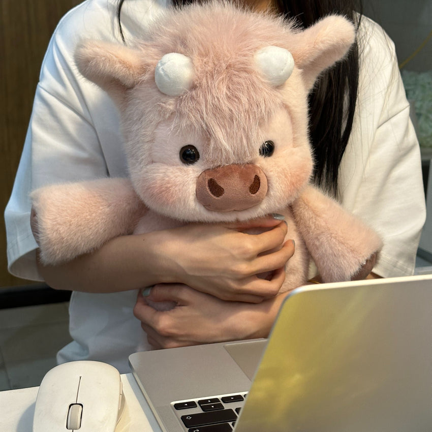 Rosie blush pink Highland cow plushie held in arms, showing its fluffy texture.