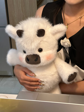 Snowy white Highland cow plushie held in arms, showing its real size and fluffy texture.